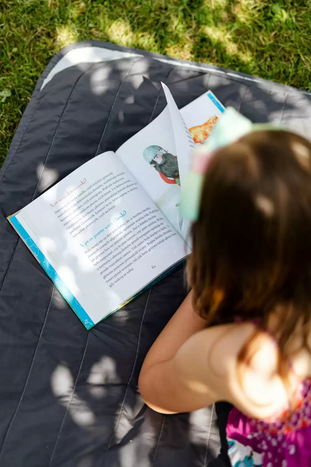 criança lendo livros infantis deitada na grama